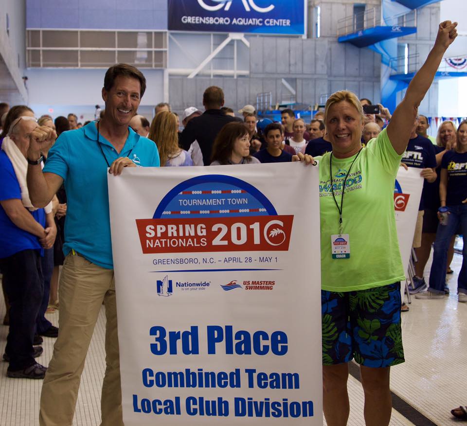 Coach Linda and swimmer Grant holding the USMS Nationals club banner